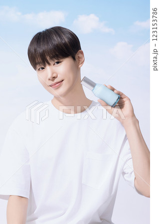 Young man holding basic cosmetics products and standing with clouds in the background Young man holding basic cosmetics products and standing with clouds in the background 123153786
