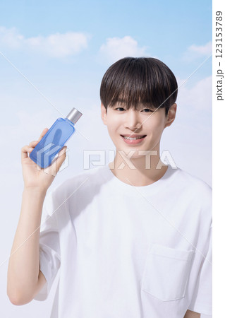 Young man holding basic cosmetics products and standing with clouds in the background 123153789