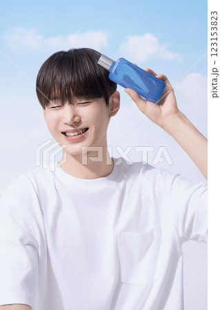 Young man holding basic cosmetics products and standing with clouds in the background 123153823