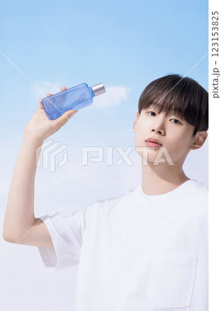 Young man holding basic cosmetics products and standing with clouds in the background 123153825