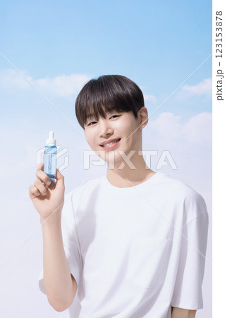Young man holding basic cosmetics products and standing with clouds in the background 123153878