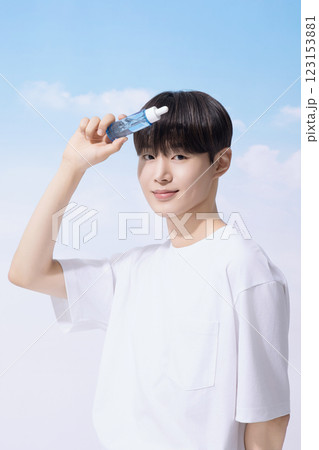 Young man holding basic cosmetics products and standing with clouds in the background Young man holding basic cosmetics products and standing with clouds in the background 123153881