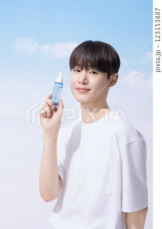 Young man holding basic cosmetics products and standing with clouds in the background 123153887