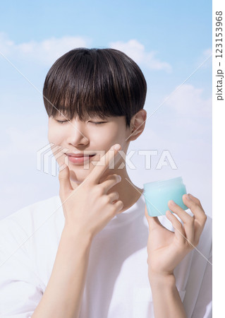 Young man holding basic cosmetics products and standing with clouds in the background Young man holding basic cosmetics products and standing with clouds in the background 123153968