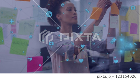 Image of network of media icons over biracial casual businesswoman brainstorming at office Image of network of media icons over biracial casual businesswoman brainstorming at office 123154026
