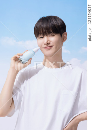 Young man holding basic cosmetics products and standing with clouds in the background Young man holding basic cosmetics products and standing with clouds in the background 123154037