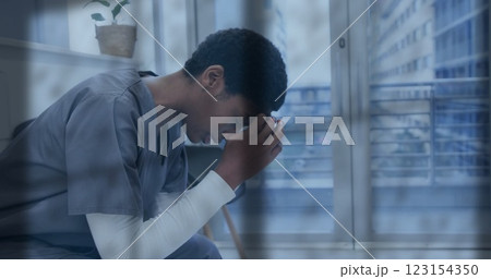 Image of rain on window over unhappy african american female doctor holding head in hands Image of rain on window over unhappy african american female doctor holding head in hands 123154350