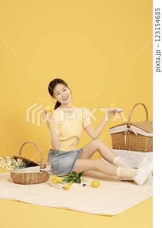 A woman in her 20s spreading out a mat and enjoying a picnic 123154685