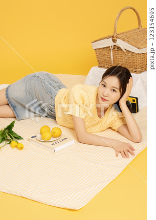 A woman in her 20s spreading out a mat and enjoying a picnic 123154695