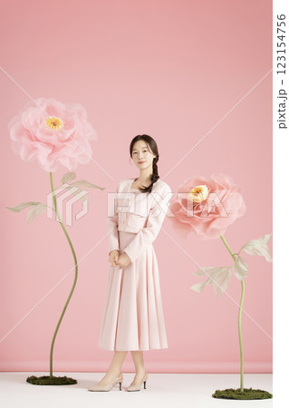 An innocent woman in her 20s wearing a pink two-piece with a large flower in the background. An innocent woman in her 20s wearing a pink two-piece with a large flower in the background. 123154756