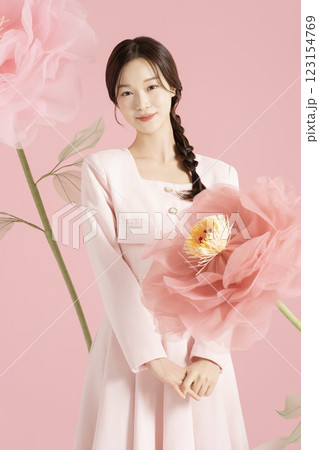 An innocent woman in her 20s wearing a pink two-piece with a large flower in the background. 123154769