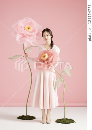 An innocent woman in her 20s wearing a pink two-piece with a large flower in the background. 123154778