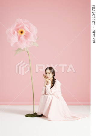An innocent woman in her 20s wearing a pink two-piece with a large flower in the background. An innocent woman in her 20s wearing a pink two-piece with a large flower in the background. 123154788