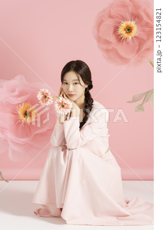 An innocent woman in her 20s wearing a pink two-piece with a large flower in the background. 123154821