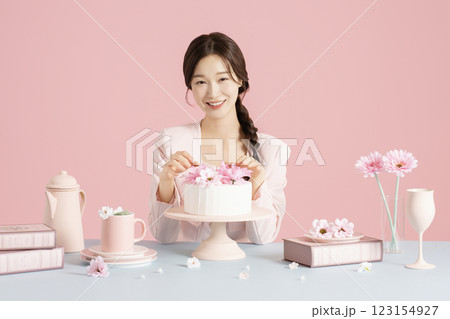A woman in her 20s smiling brightly while sitting in front of a cake 123154927