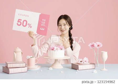 A woman in her 20s sitting in front of a cake and holding a coupon 123154962
