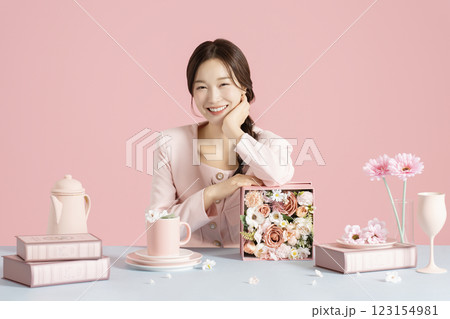 A woman in her 20s smiling while sitting in front of a table set with a bright spring concept. 123154981