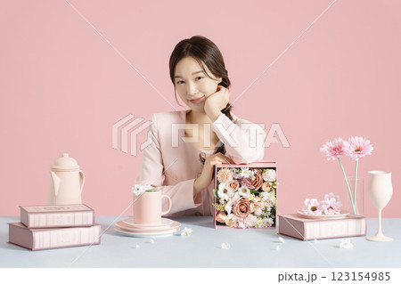 A woman in her 20s smiling while sitting in front of a table set with a bright spring concept. A woman in her 20s smiling while sitting in front of a table set with a bright spring concept. 123154985