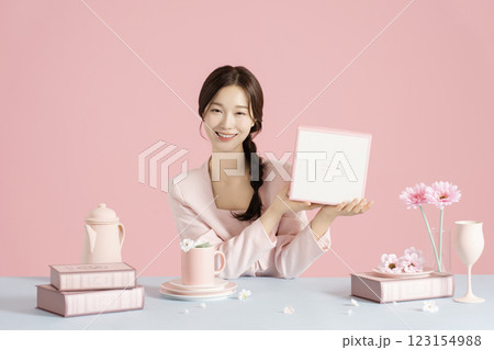 A woman in her 20s sitting in front of a table set with a bright spring concept and holding a box. 123154988