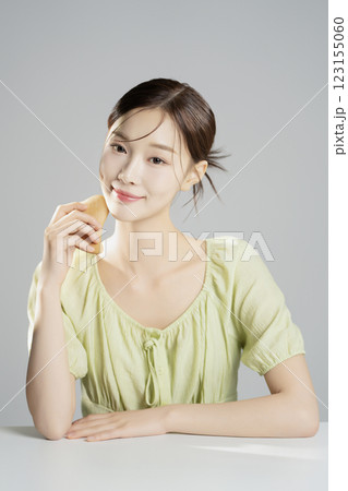A pretty woman in her 20s wearing bright clothes, sitting and posing with cosmetics 123155060