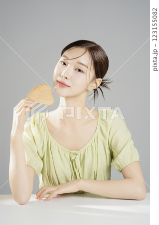 A pretty woman in her 20s wearing bright clothes, sitting and posing with cosmetics 123155082