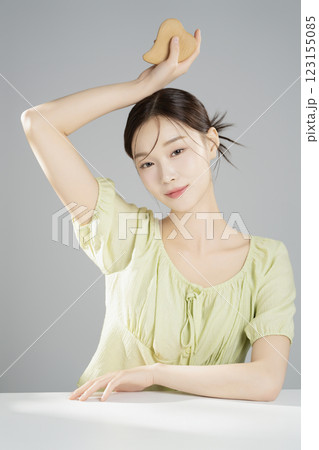 A pretty woman in her 20s wearing bright clothes, sitting and posing with cosmetics A pretty woman in her 20s wearing bright clothes, sitting and posing with cosmetics 123155085