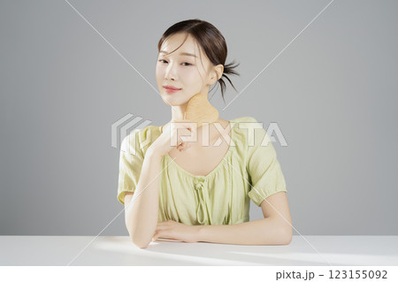 A pretty woman in her 20s wearing bright clothes, sitting and posing with cosmetics 123155092