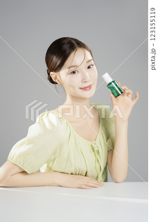 A pretty woman in her 20s wearing bright clothes, sitting and posing with cosmetics A pretty woman in her 20s wearing bright clothes, sitting and posing with cosmetics 123155119