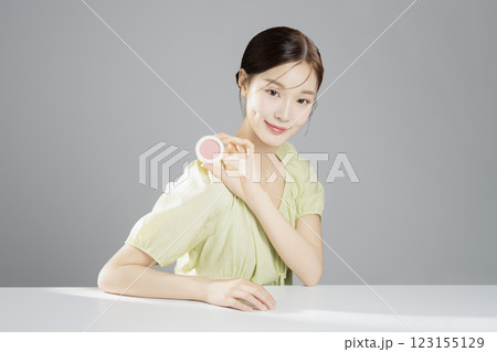 A pretty woman in her 20s wearing bright clothes, sitting and posing with cosmetics A pretty woman in her 20s wearing bright clothes, sitting and posing with cosmetics 123155129