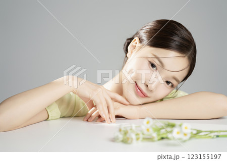 A woman in her 20s posing prone in front of flowers 123155197