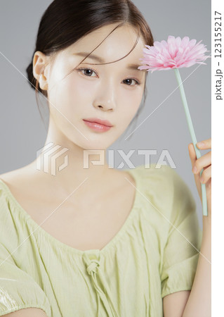 A woman in her 20s posing with a pink flower 123155217