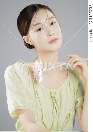 A woman in her 20s posing with a pink flower 123155232