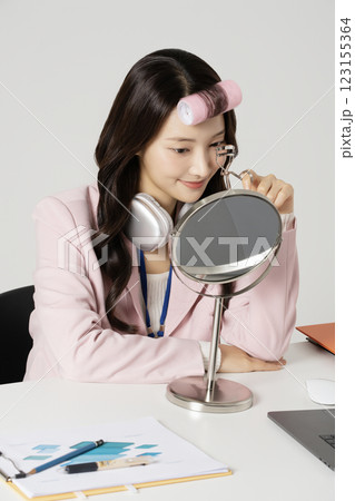 MZ employee fixing her makeup with a hair roller 123155364