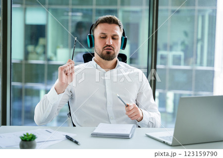 Professional Businessman Working in an Office While Listening to Music Professional Businessman Working in an Office While Listening to Music 123159790