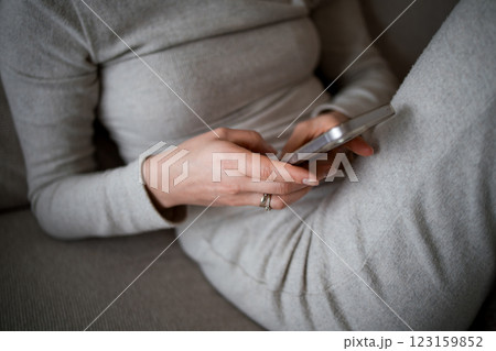 Caucasian female adult using smartphone in casual gray outfit at home 123159852