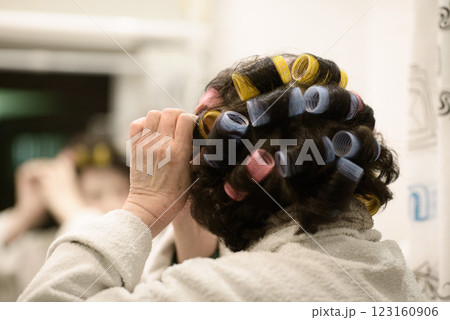 Elderly Lady Adjusting Curler in Bathroom Mirror 123160906