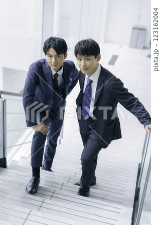 オフィスビルの階段に立つ若いビジネスマン2人のポートレート 縦位置 オフィスビルの階段に立つ若いビジネスマン2人のポートレート 縦位置 123162004