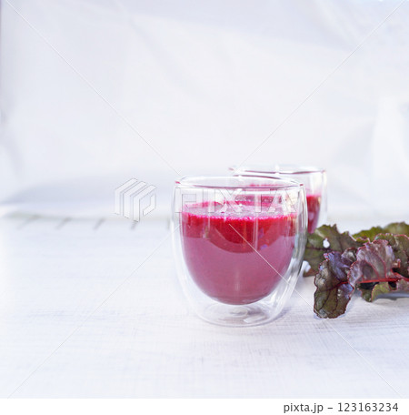 A cup of fresh beetroot juice with leaves on table. A cup of fresh beetroot juice with leaves on table. 123163234