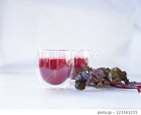 A cup of fresh beetroot juice with leaves on table. 123163235