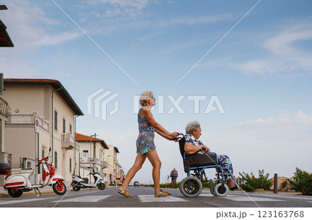 Daughter pushes her elderly mother in wheelchair 123163768
