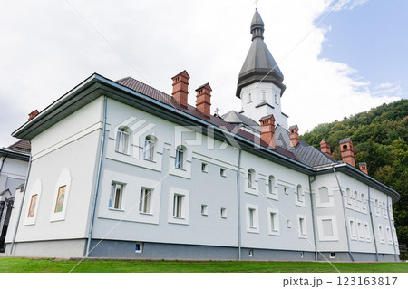 Modern monastery building with a tall tower and green hills in the background. Modern monastery building with a tall tower and green hills in the background. 123163817