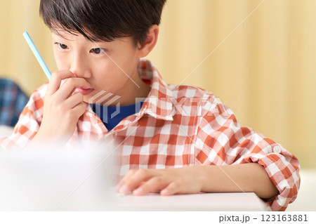 鼻の頭をかきながら勉強する男子小学生 123163881