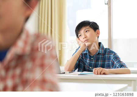 頬杖をついてよそ見をする小学校高学年男子 123163898