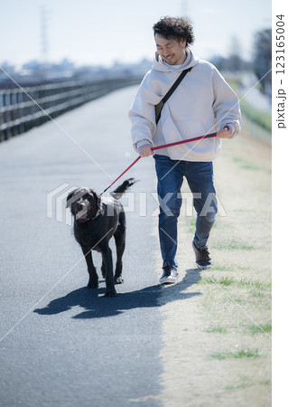 河川敷で大型犬の散歩を楽しむ男性 123165004