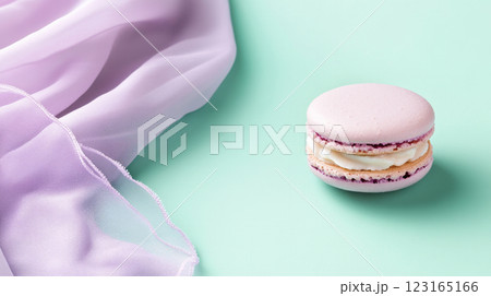 Lavender macaron with cream filling on pastel mint surface alongside flowing silk fabric. Concept of elegant desserts, gourmet treats, refined taste, pastel colors 123165166