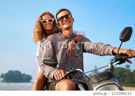 Smiling couple on motorbike. Man and woman ride scooter by ocean. Romantic, carefree adventure on beach. Love, joy, travel in tropical paradise. Valentine day. Smiling couple on motorbike. Man and woman ride scooter by ocean. Romantic, carefree adventure on beach. Love, joy, travel in tropical paradise. Valentine day. 123166215