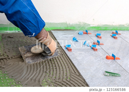 Tiler at work applies cement glue to the floor to install tiles. Construction. 123166586