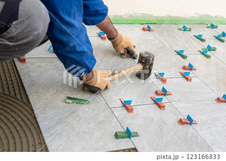 Tiler at work with rubber tile hammer. Construction. Tiler at work with rubber tile hammer. Construction. 123166833