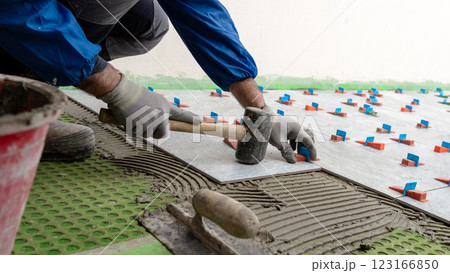 Tiler at work with rubber tile hammer. Construction. 123166850