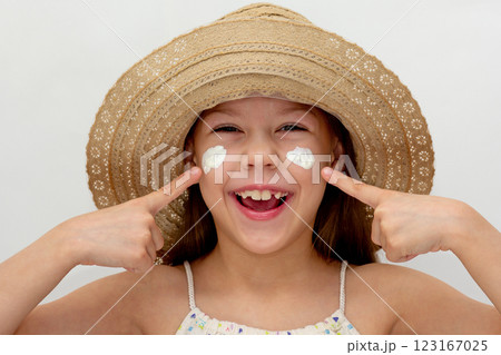 Portrait of caucasian smiling child in straw hat showing on cheeks with cream of 6 7 years looking at camera 123167025